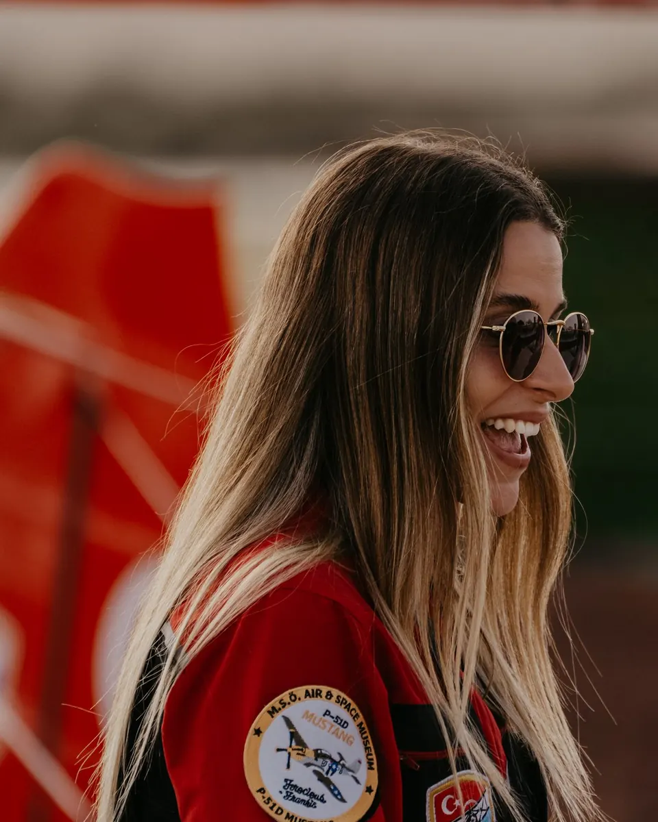 Marta Zielińska w kurtce pilotki, uśmiechnięta, na lotnisku
