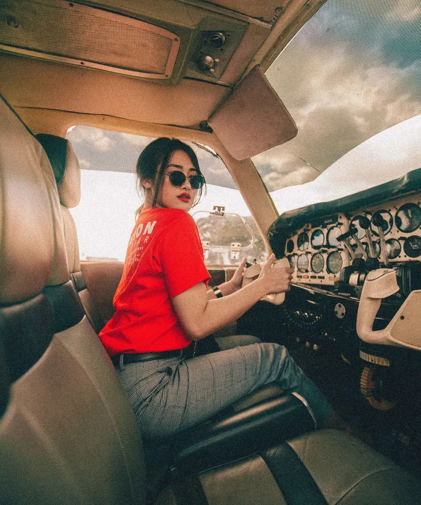 Uśmiechnięta pilotka w okularach przeciwsłonecznych za sterami